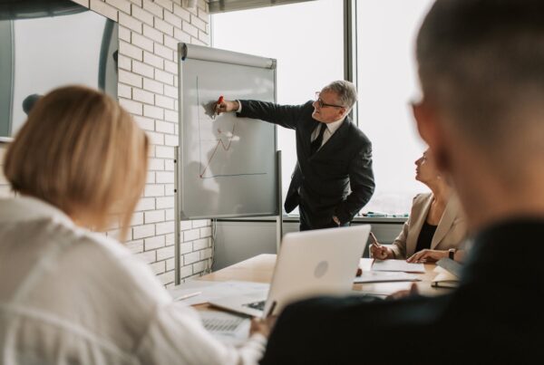 A confident professional presenting ideas in a modern office, with colleagues attentively listening, symbolizing workplace influence and leadership.